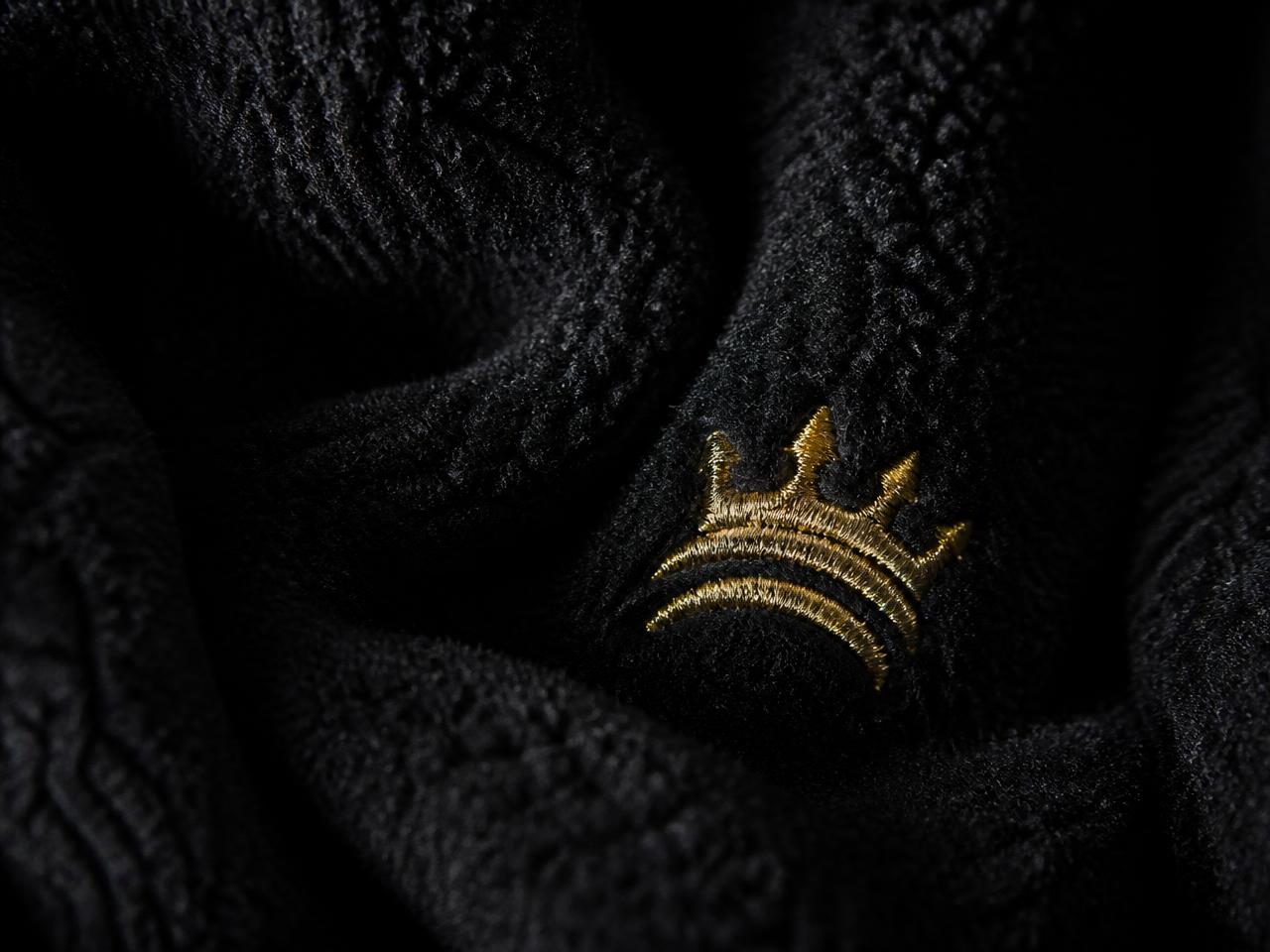 Macro detail of Ryvora heavyweight black fleece with gold embroidered emblem